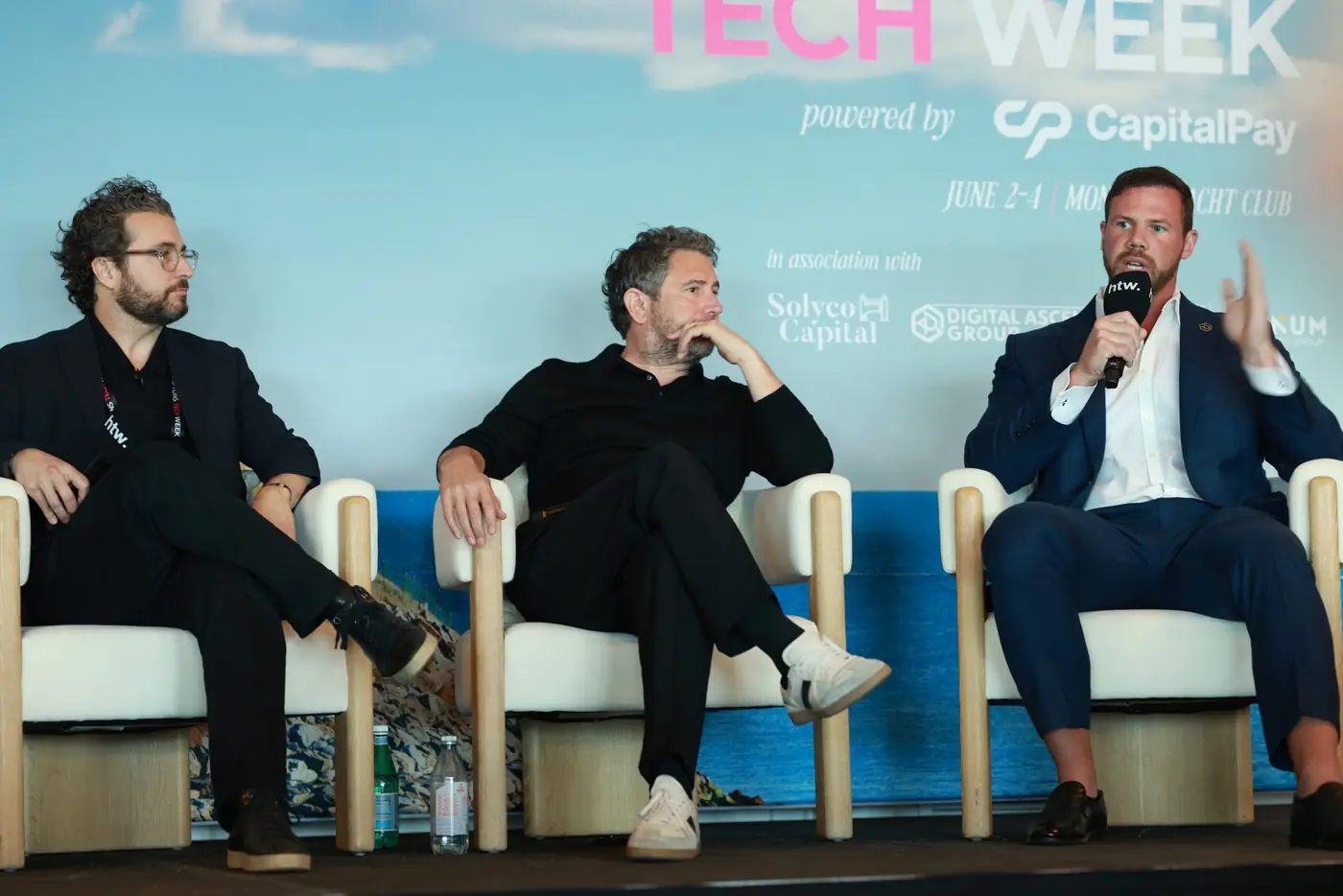 Jake Claver on a three-person panel at Tech Week, speaking into a microphone