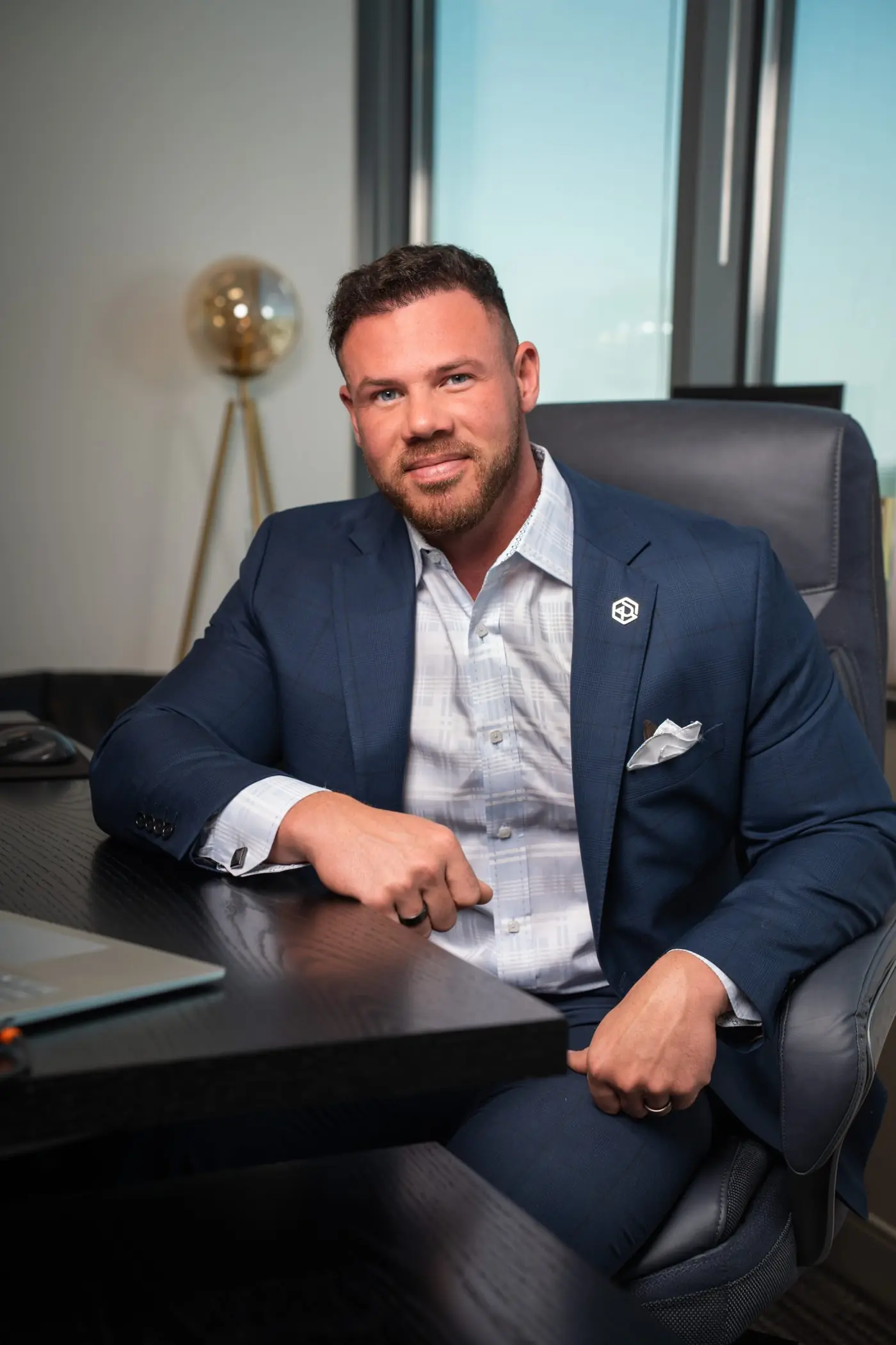 Jake Claver seated at a desk in a navy suit